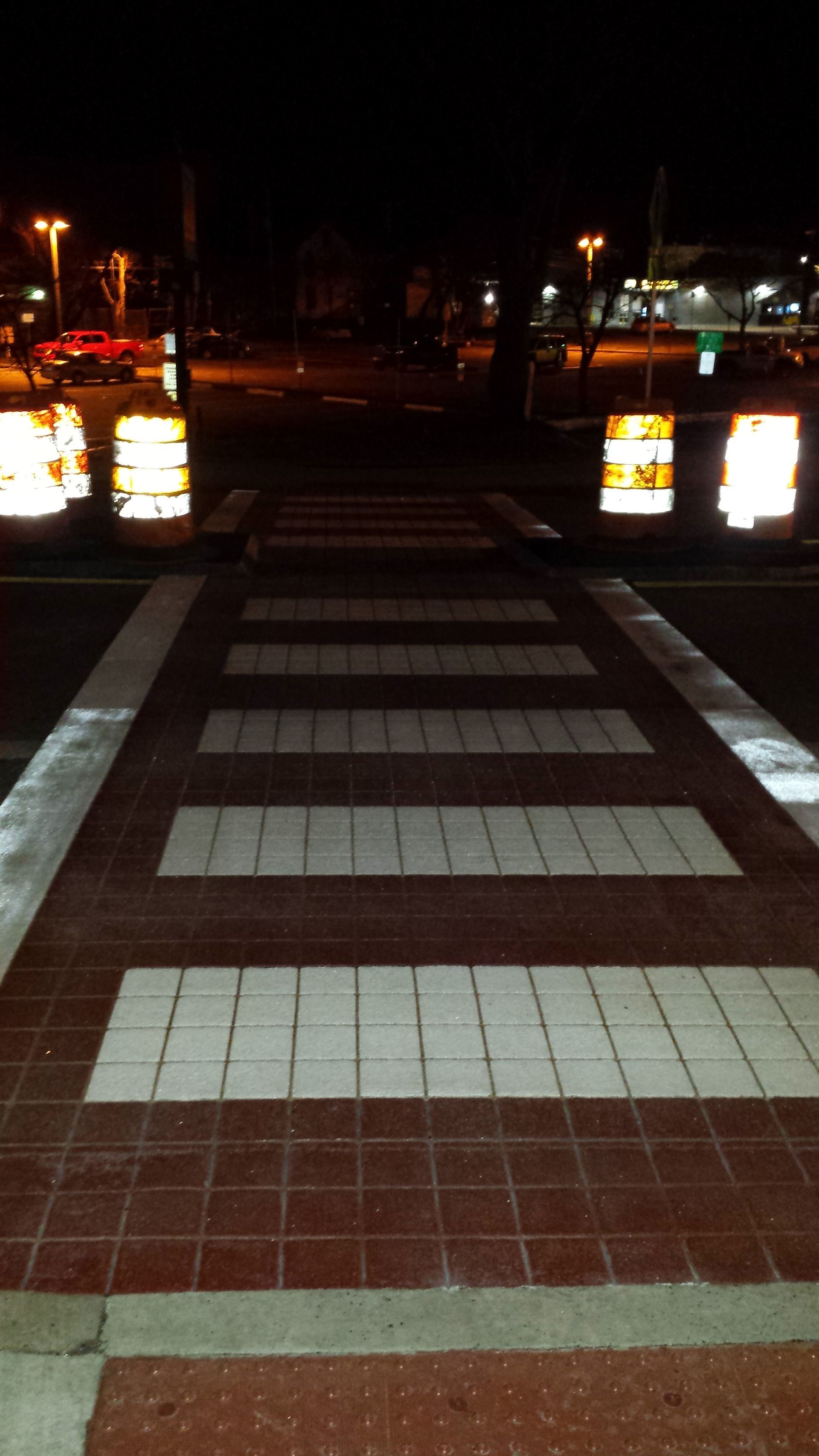 A brick walkway with a crosswalk at night