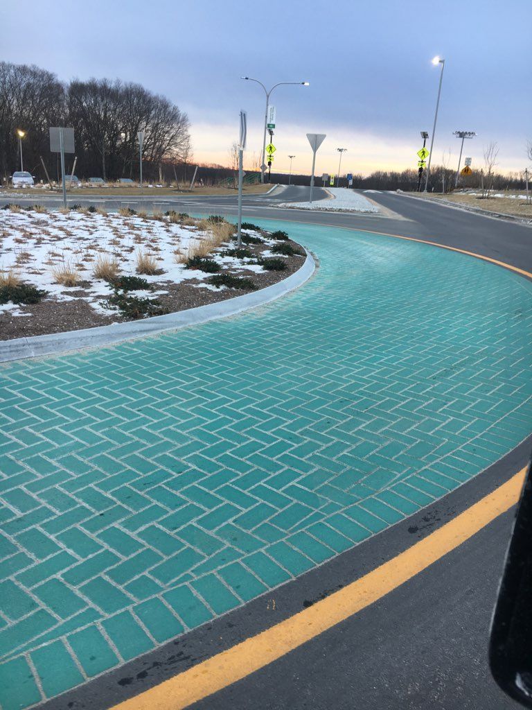 A green brick road with a yellow line on the side of it