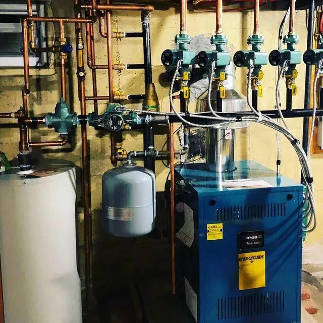 Boiler room with blue furnace, copper pipes, gauges, and a water tank