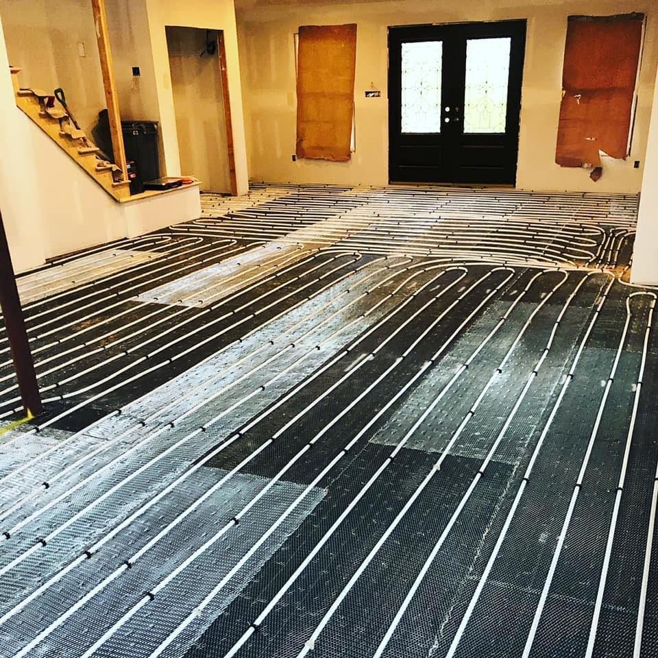 Kitchen or room under renovation with dark subflooring and white adhesive lines, doors and windows at the back.