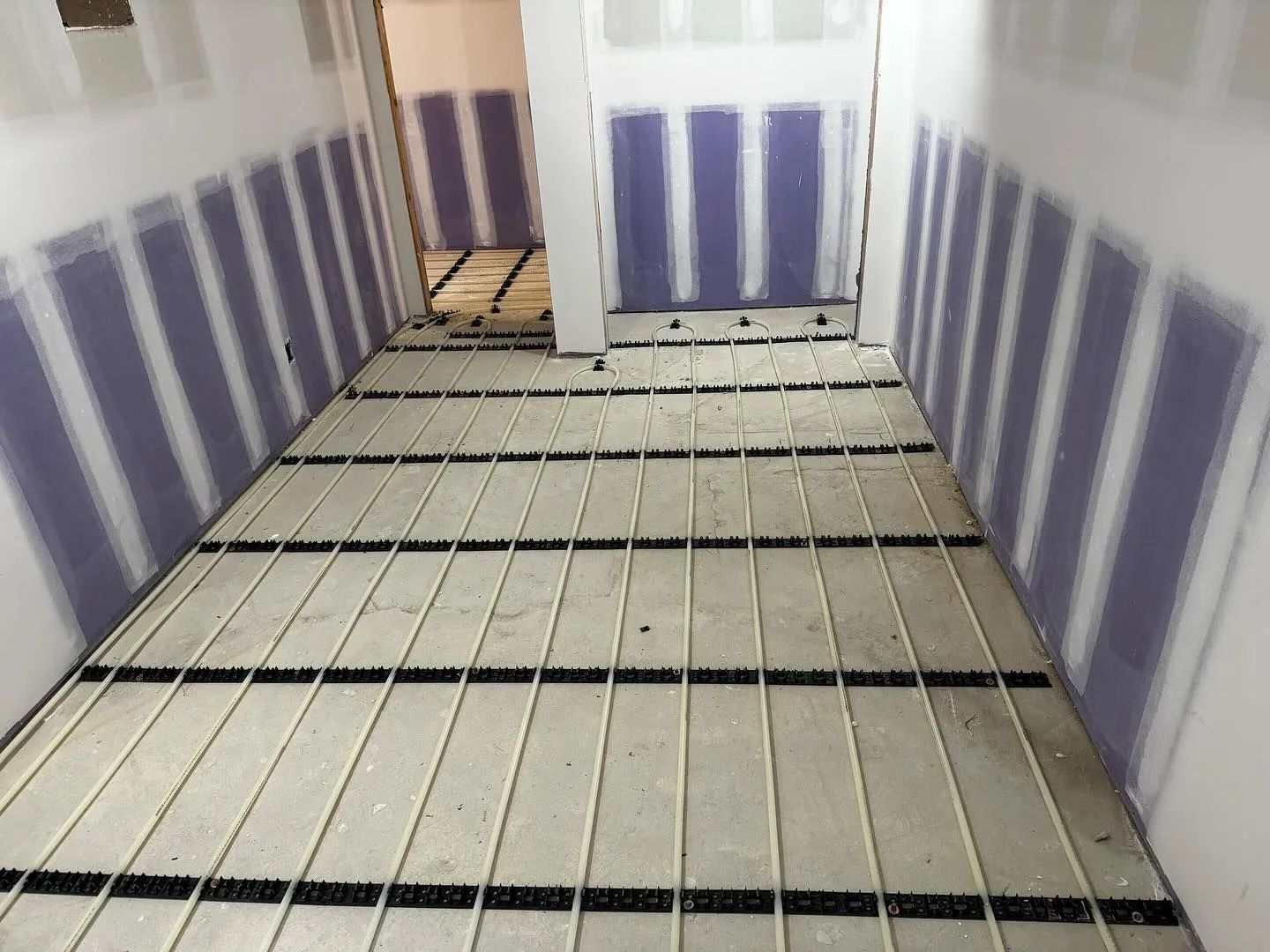 Narrow unfinished hallway with purple-striped walls and exposed floor joists.