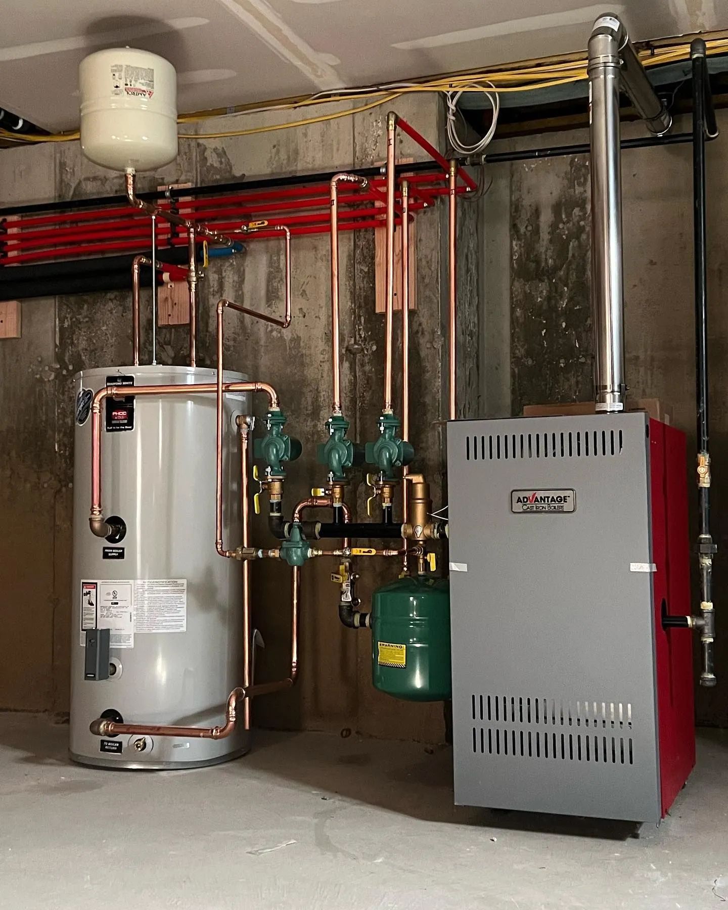 Basement utility room with water heater, boiler, pipes, and an expansion tank.
