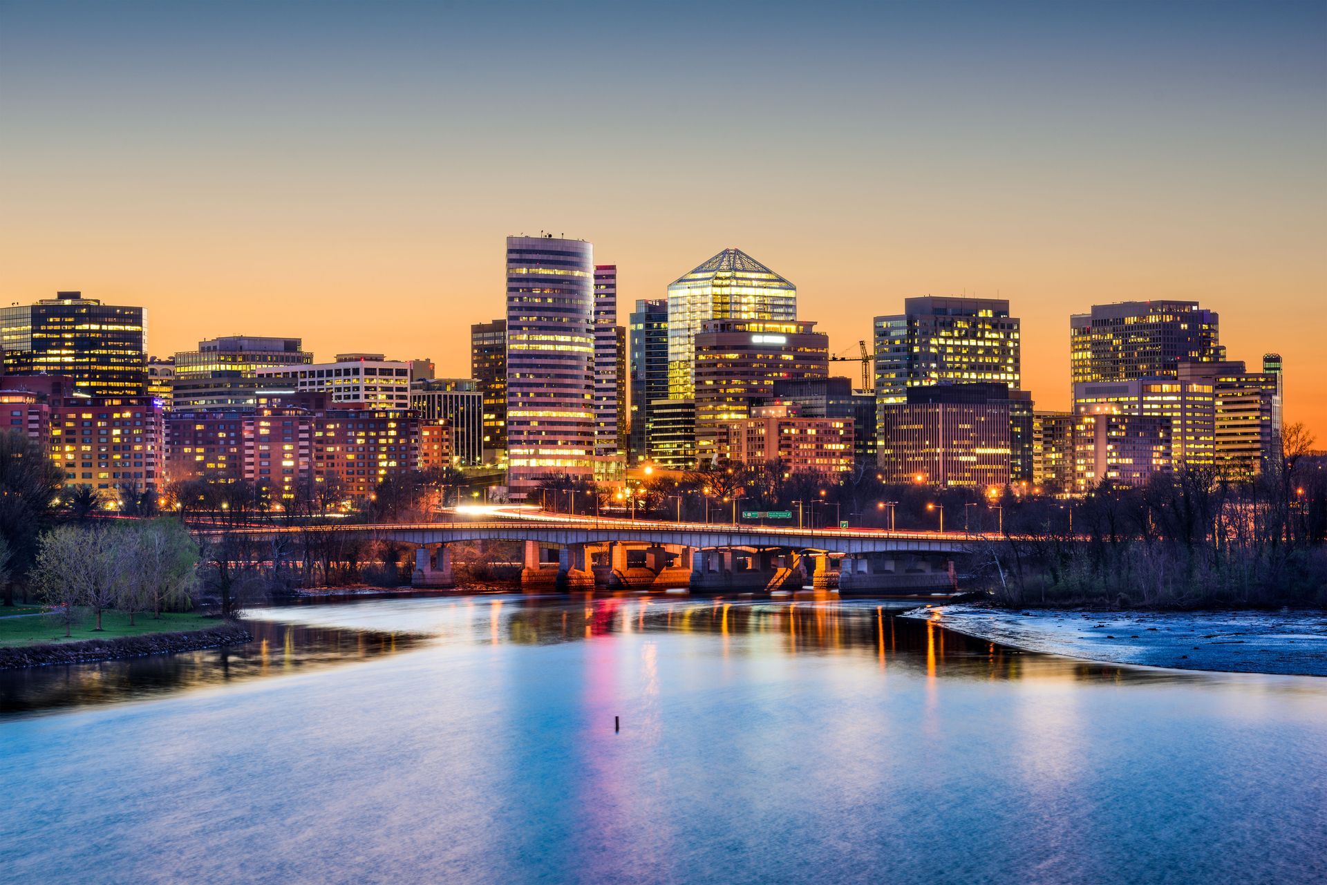 A city skyline over a body of water with a bridge in the foreground.