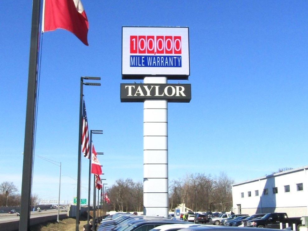 A taylor mile warranty sign with cars parked in front of it.