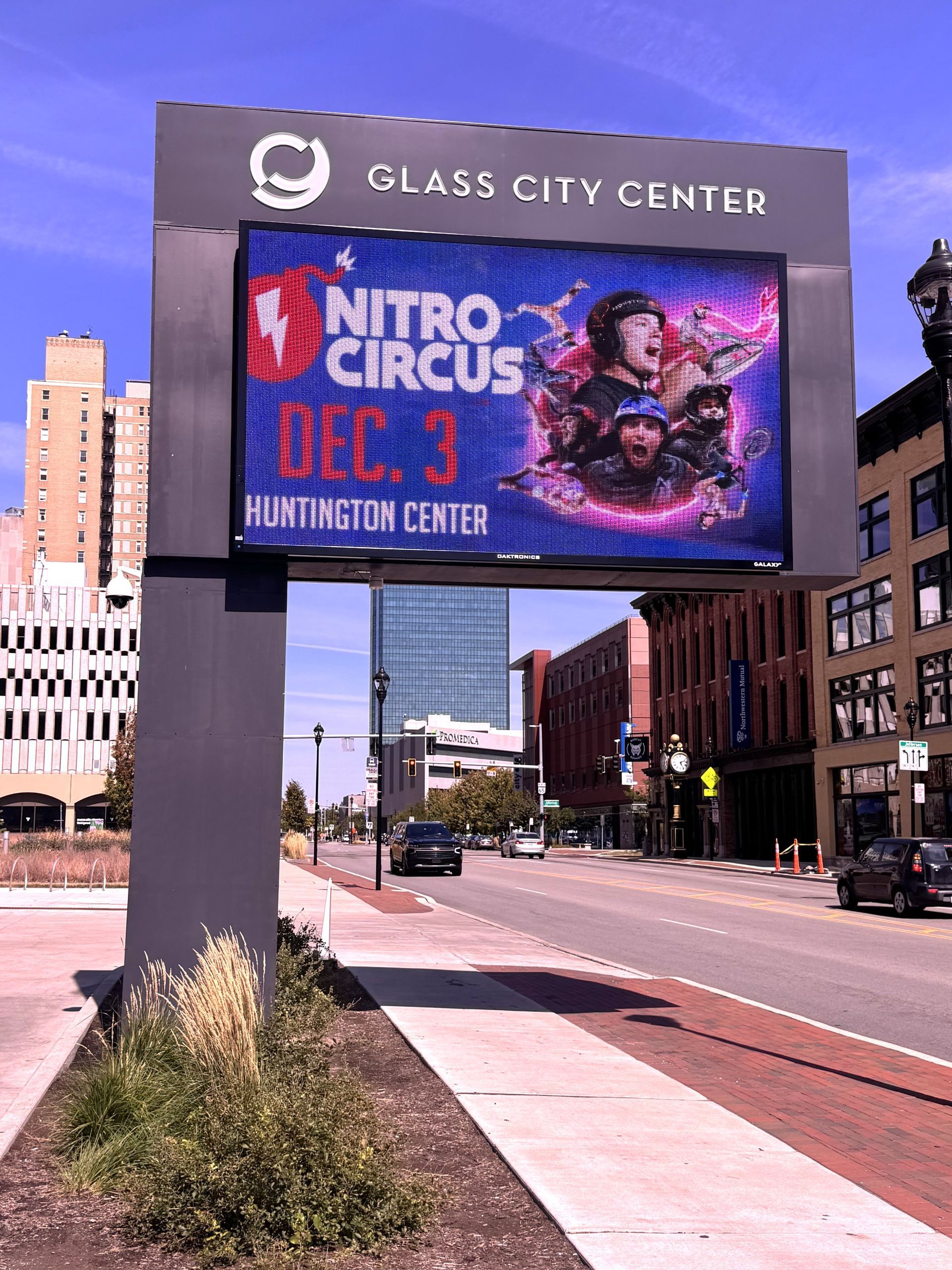 A billboard for nitro circus is on the side of a city street.