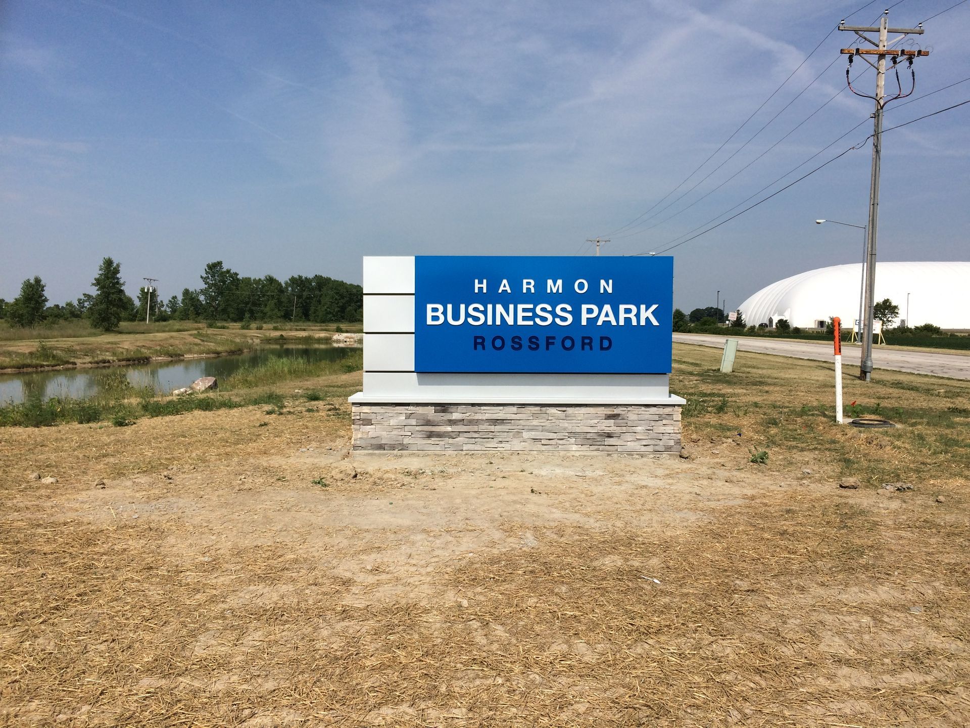A blue and white business park sign in a field