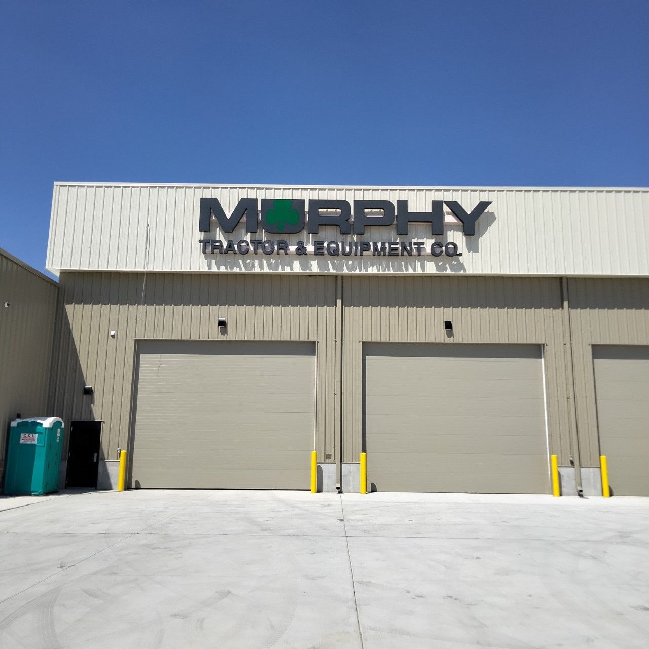 Sign for Murphy Tractor & Equipment Co. above tan garage doors; blue sky in the background.