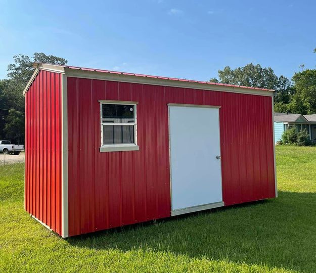 Red portable shed with a white door and window on a grassy lawn.