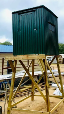 Green shed on a raised wooden support frame at a construction site