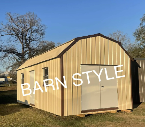 Tan barn-style shed with double doors in a grassy yard under a blue sky