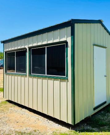 Small beige portable office shed with dark windows and a white door outdoors under a blue sky