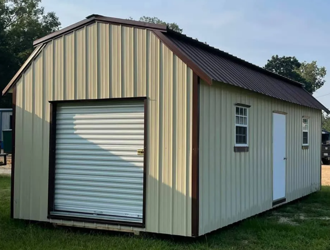 Beige metal storage shed with white roll-up door and side window on grass