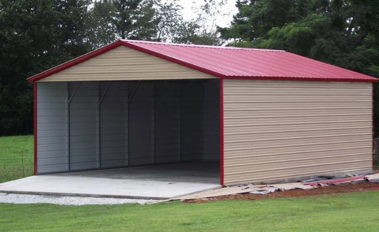 Small beige metal garage with red roof and trim, open front, sitting on a grassy lawn.