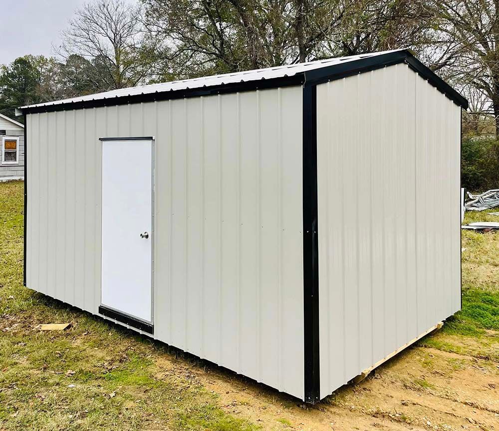 Small beige metal shed with a white door and dark trim on grassy ground.