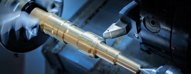 A CNC machine cutting a brass rod.