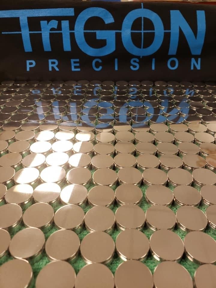 Close-up of a pile of shiny, machined metal cylinders with rust-colored bases.