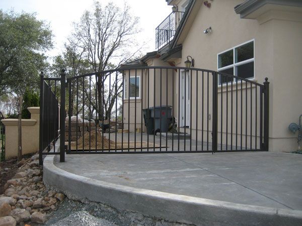 A fence surrounds a concrete walkway in front of a house
