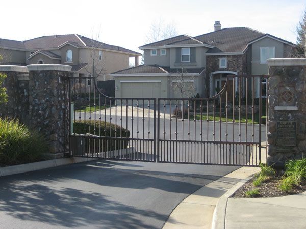 A gated driveway with a large house in the background