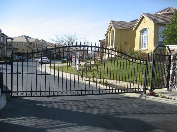 A wrought iron gate is open in front of a house