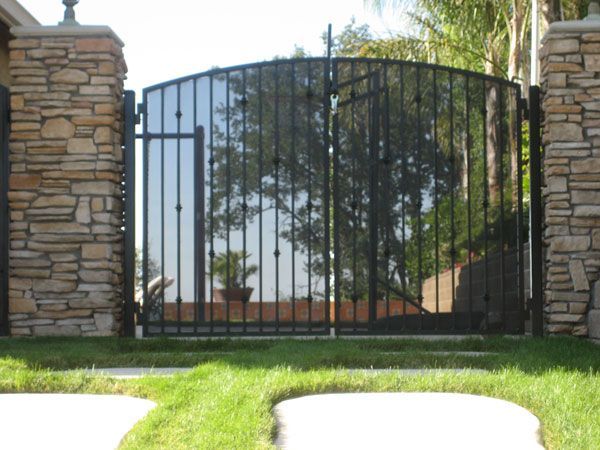 A wrought iron gate with a stone wall behind it