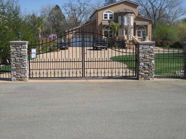 A large house is behind a wrought iron gate