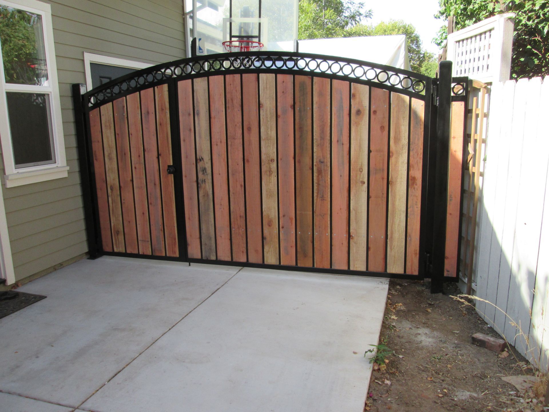 A wooden gate with a black frame is in front of a house