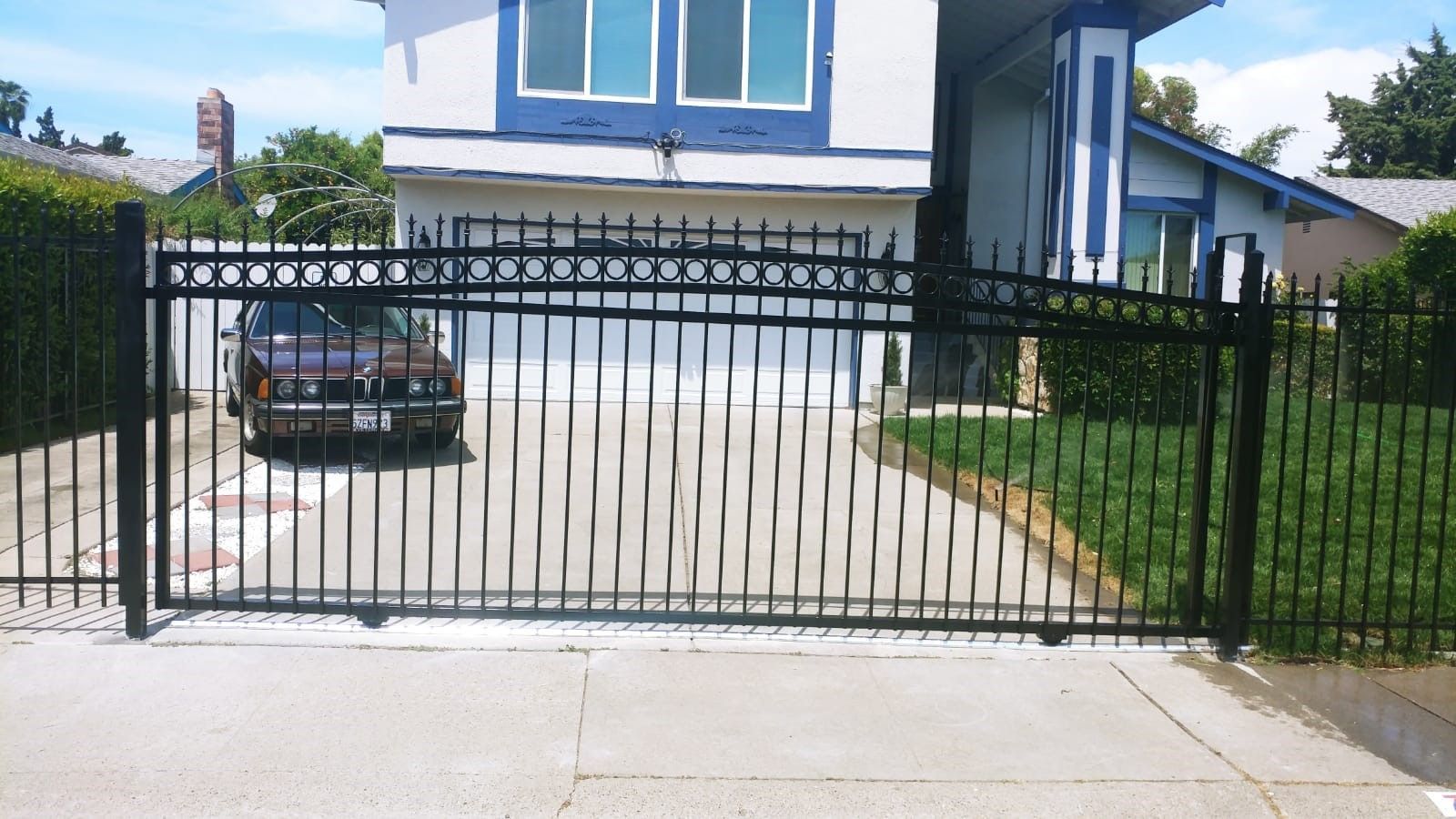 A car is parked in front of a house behind a gate