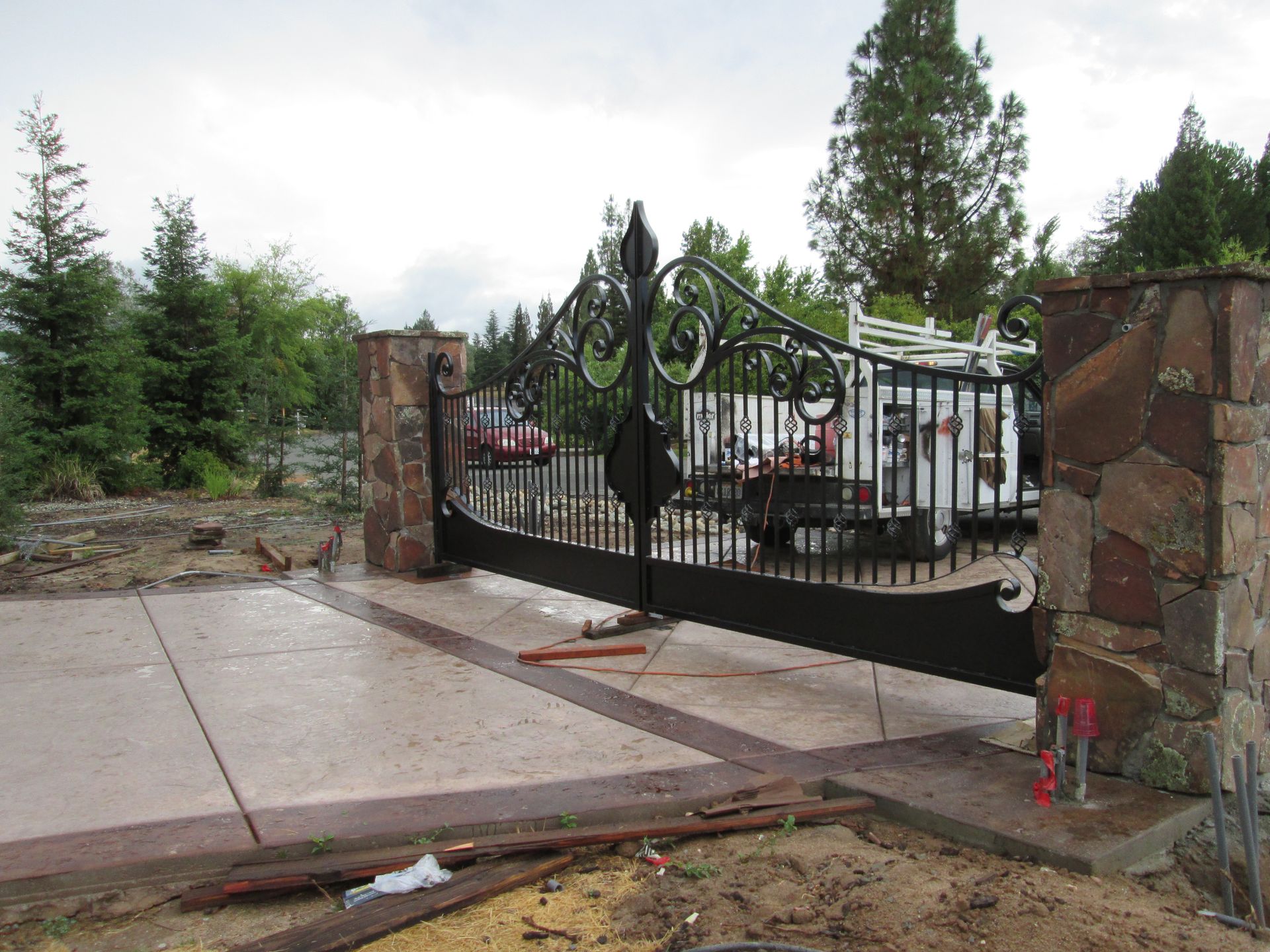 A black gate with a stone pillar in front of it