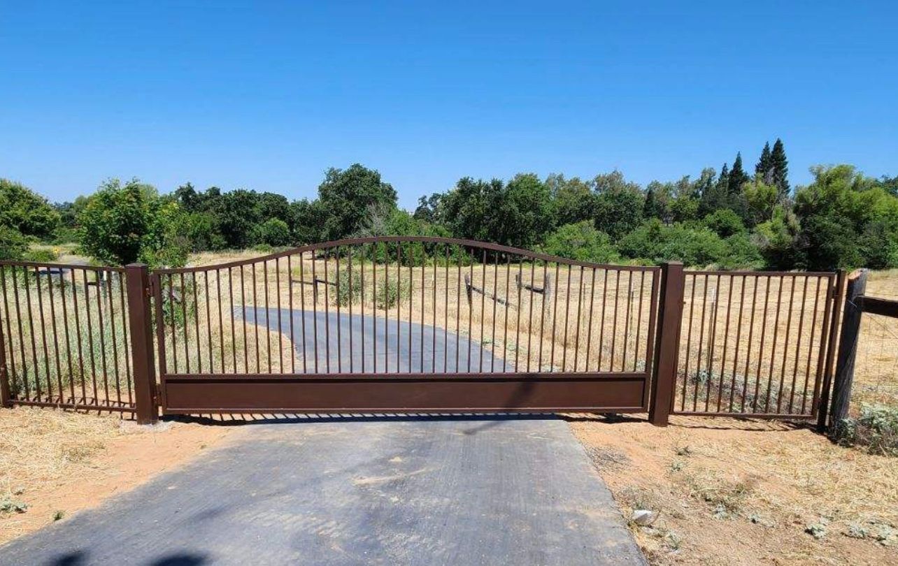A fence surrounds a dirt road with trees in the background