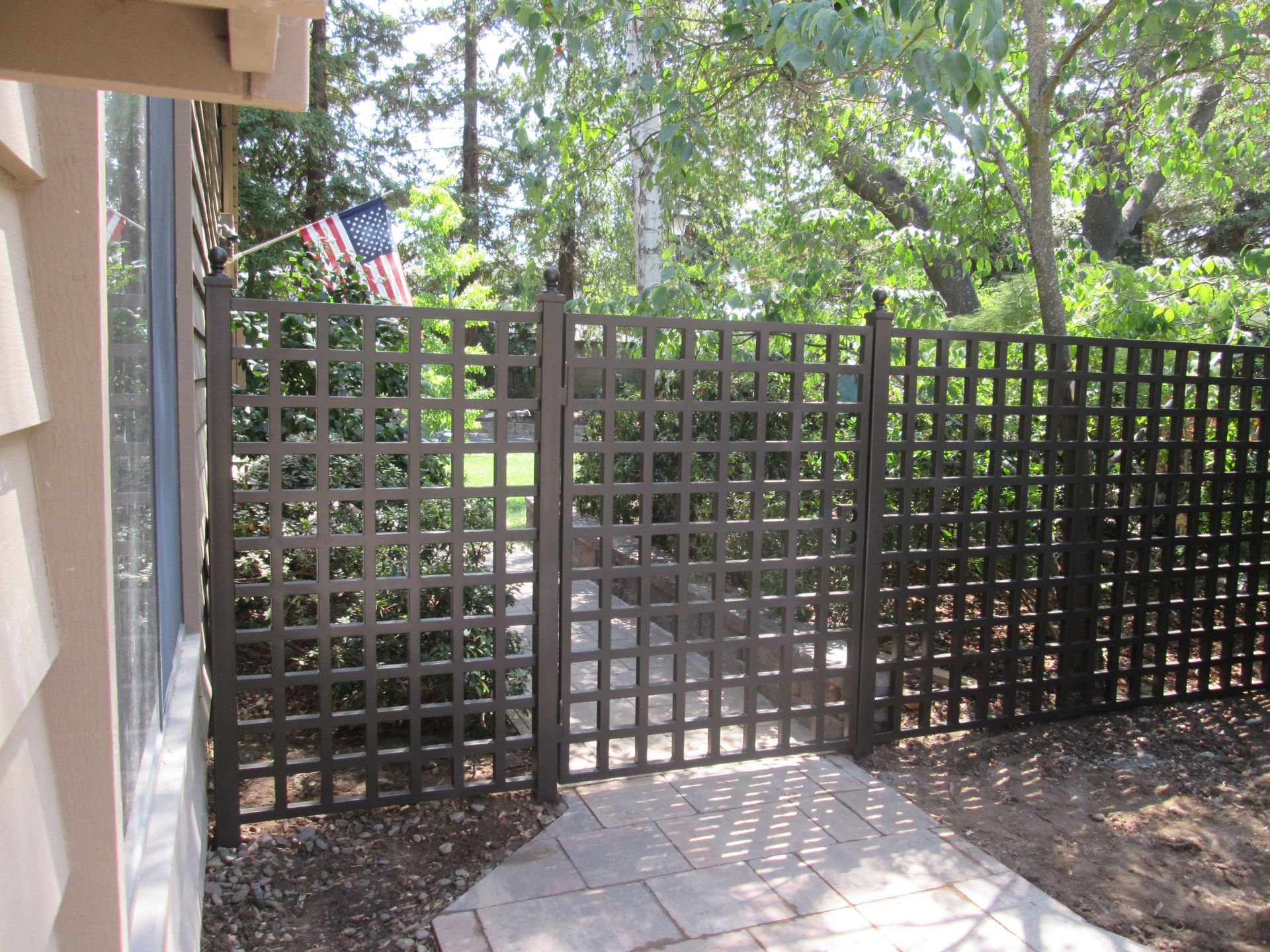 A wooden fence surrounds a patio with trees in the background
