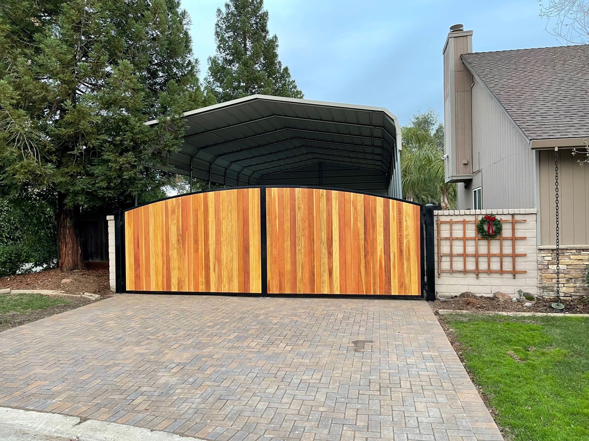 A wooden gate is in the driveway of a house