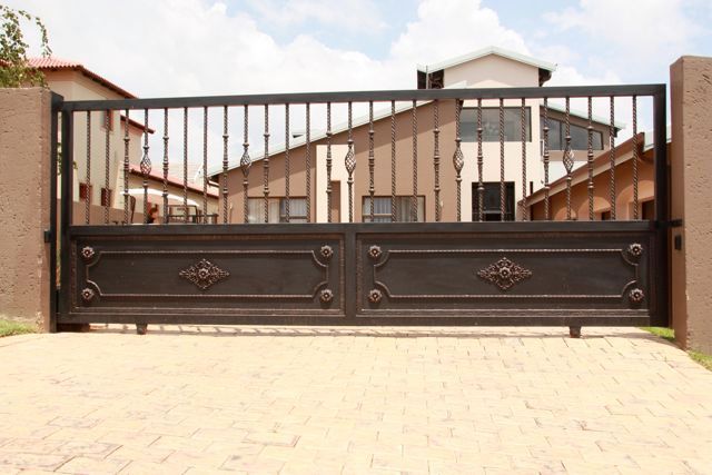 A sliding gate is open to a driveway in front of a house