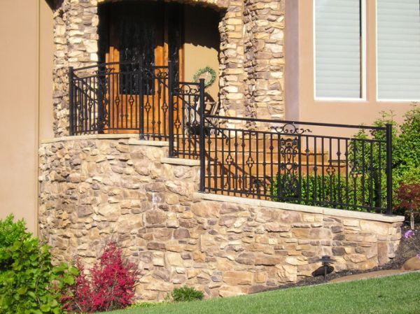 A house with a stone wall and a wrought iron railing