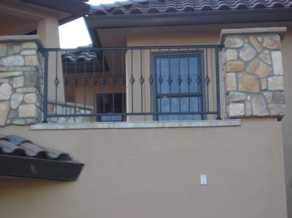 A balcony on the side of a building with a wrought iron railing