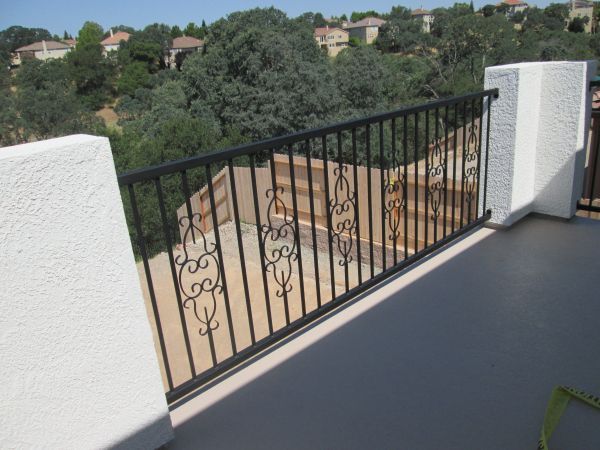 A balcony with a wrought iron railing and a view of trees