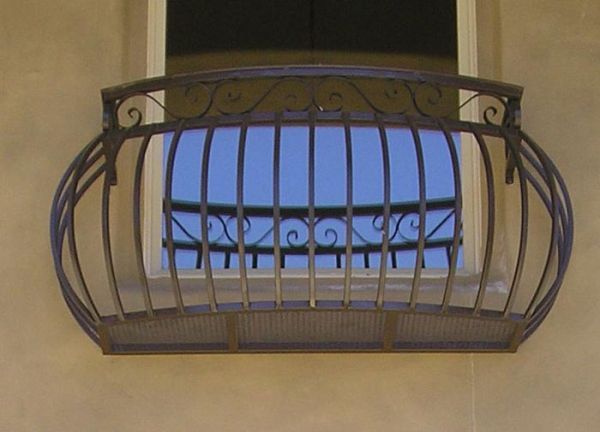 A balcony with a wrought iron railing over a window