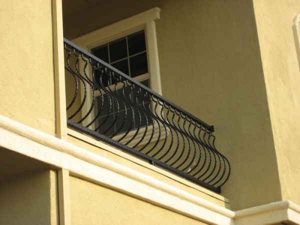 A balcony on the side of a building with a wrought iron railing