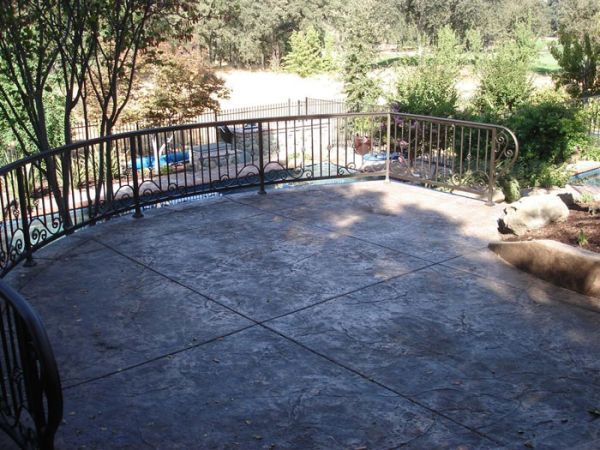 A patio with a metal railing and trees in the background