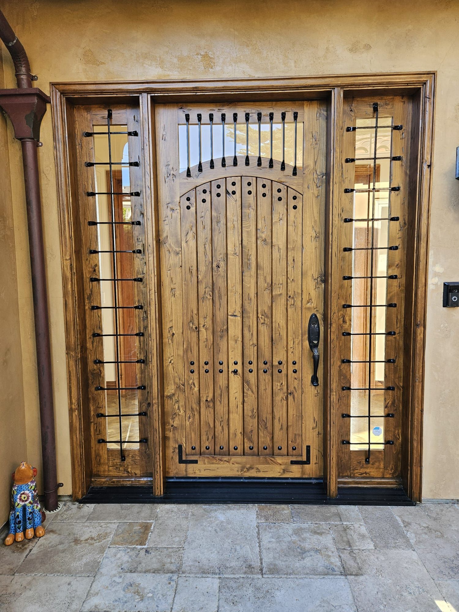 Wooden front door with glass sidelights and decorative ironwork on a stone entryway