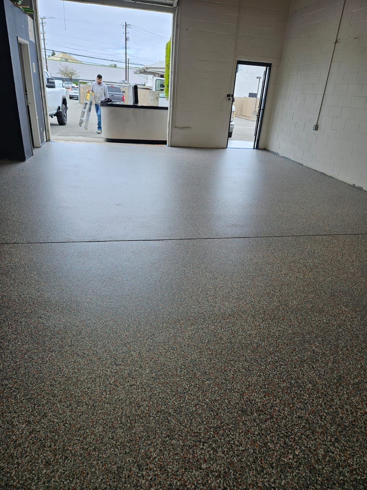 Empty warehouse interior with speckled concrete floor and open roll-up doorway to the outside