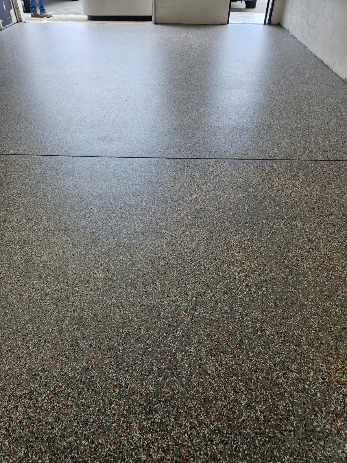 Low-angle view of a speckled gray floor in a bright indoor hallway.