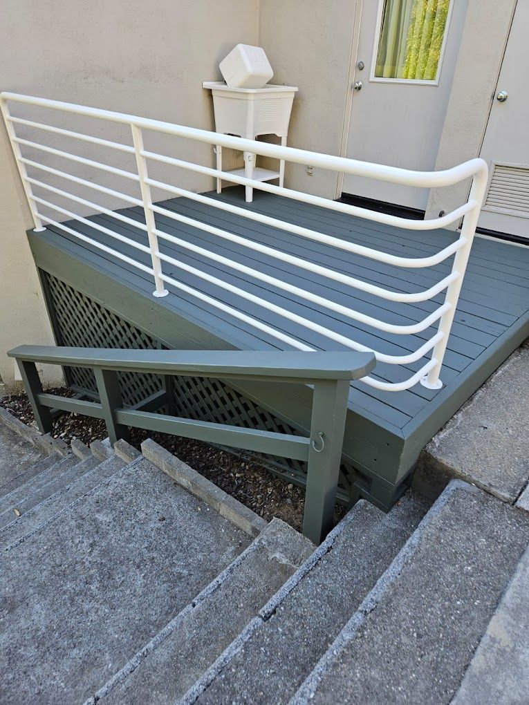 White-railed wheelchair ramp beside concrete steps on a building exterior