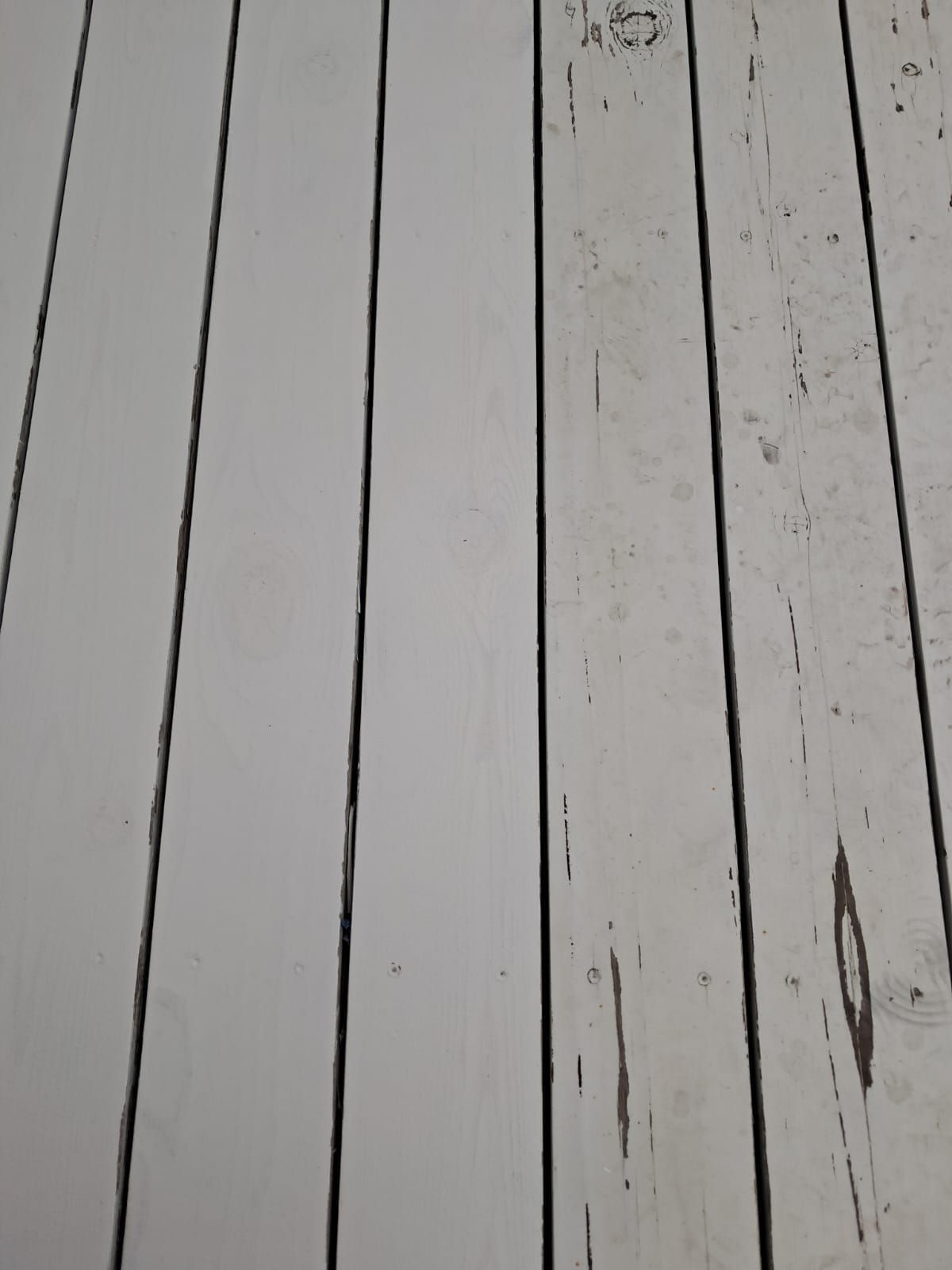 Close-up of weathered gray wooden planks with dark seams and scratches.