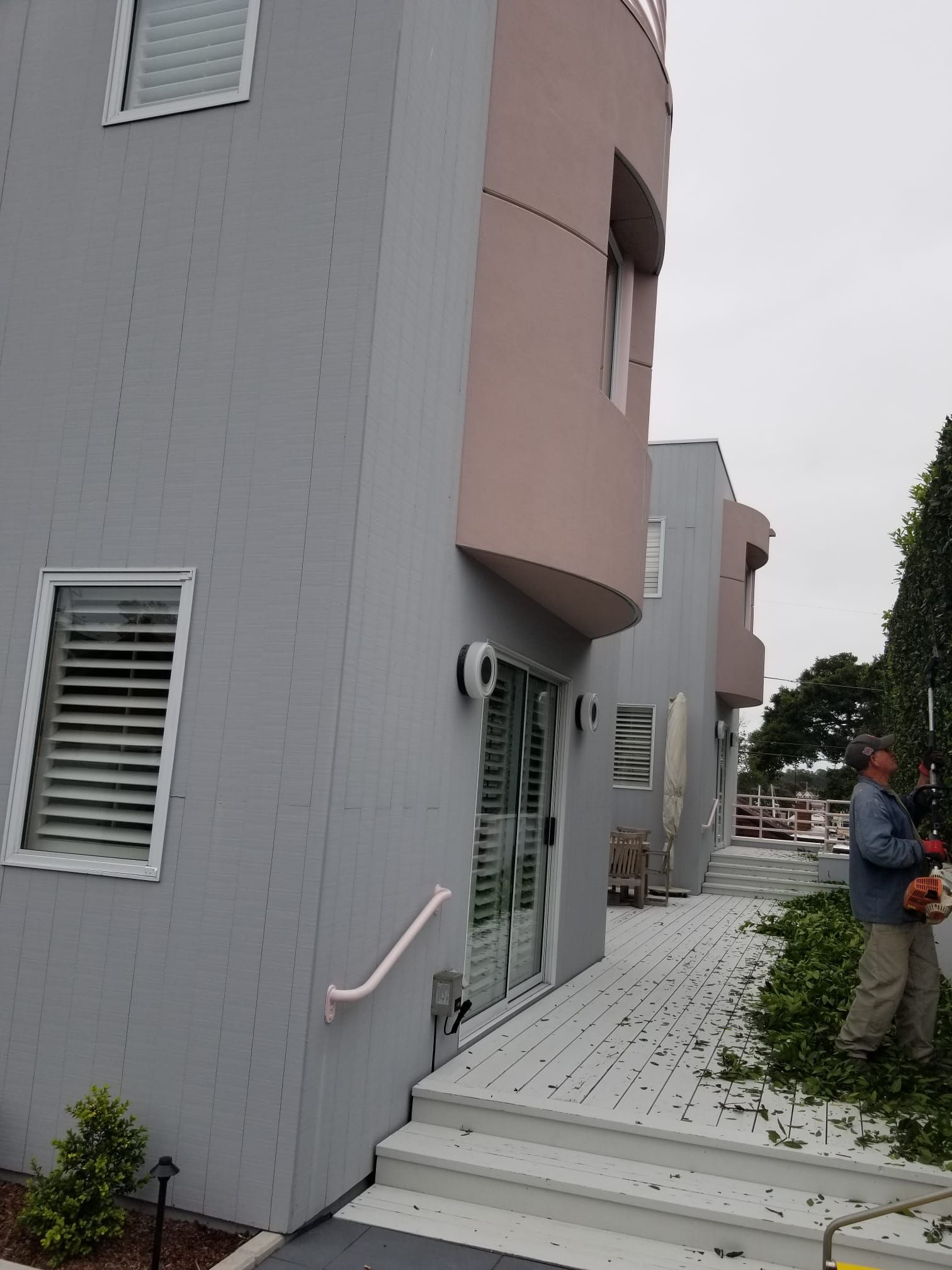 Modern apartment walkway with gray buildings, white railings, and a person standing near the path
