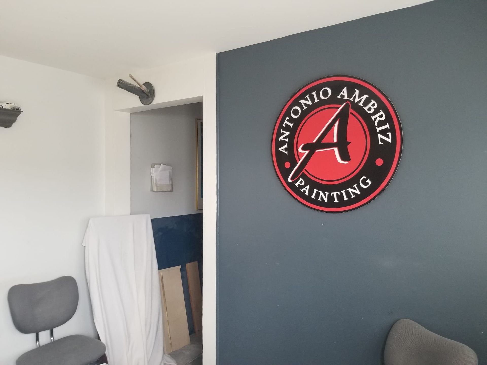 Office interior with dark blue accent wall and circular Antonio Ambroz Painting logo sign