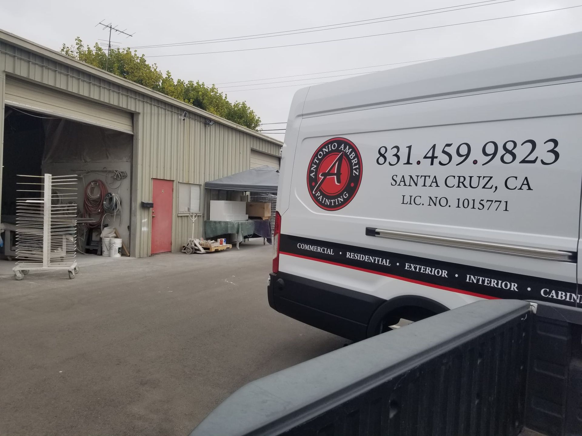 White Santa Cruz CA service van parked outside a warehouse with open garage bays