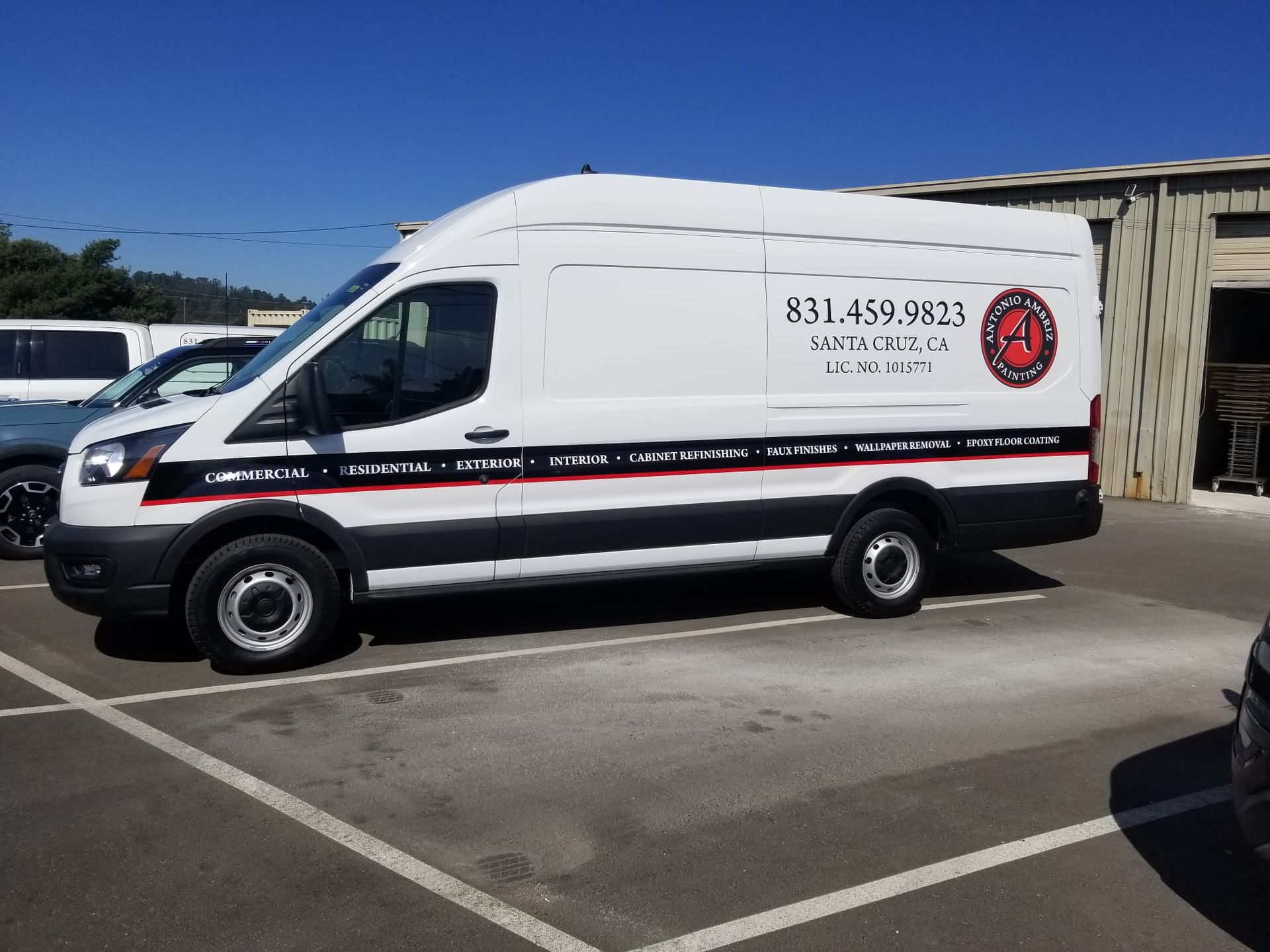 White utility van with red and black stripes parked in a lot under a blue sky