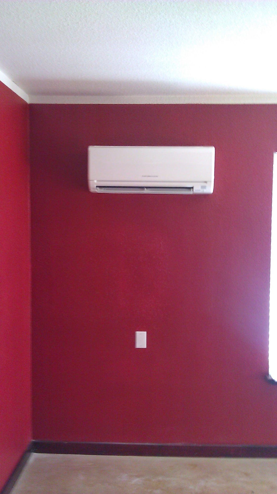 A room with red walls and a white air conditioner on the wall.