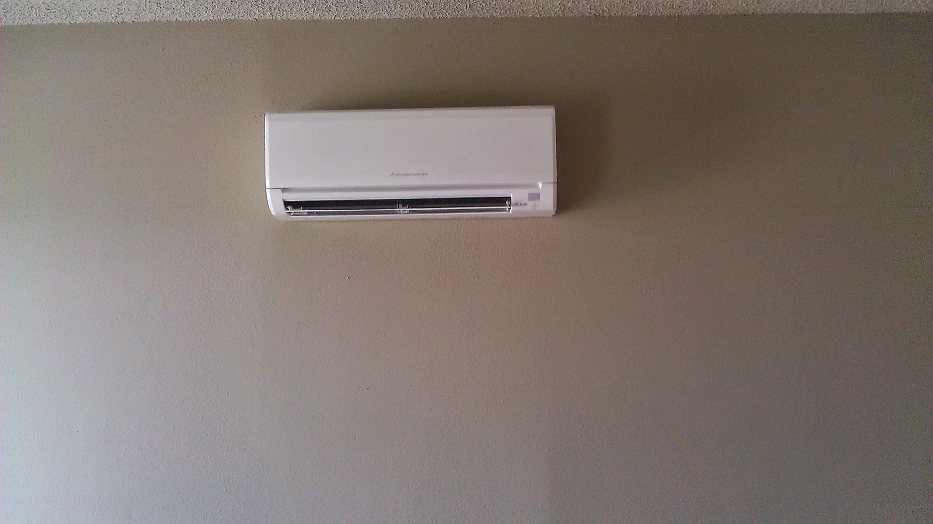 A white air conditioner is hanging on a wall in a room.