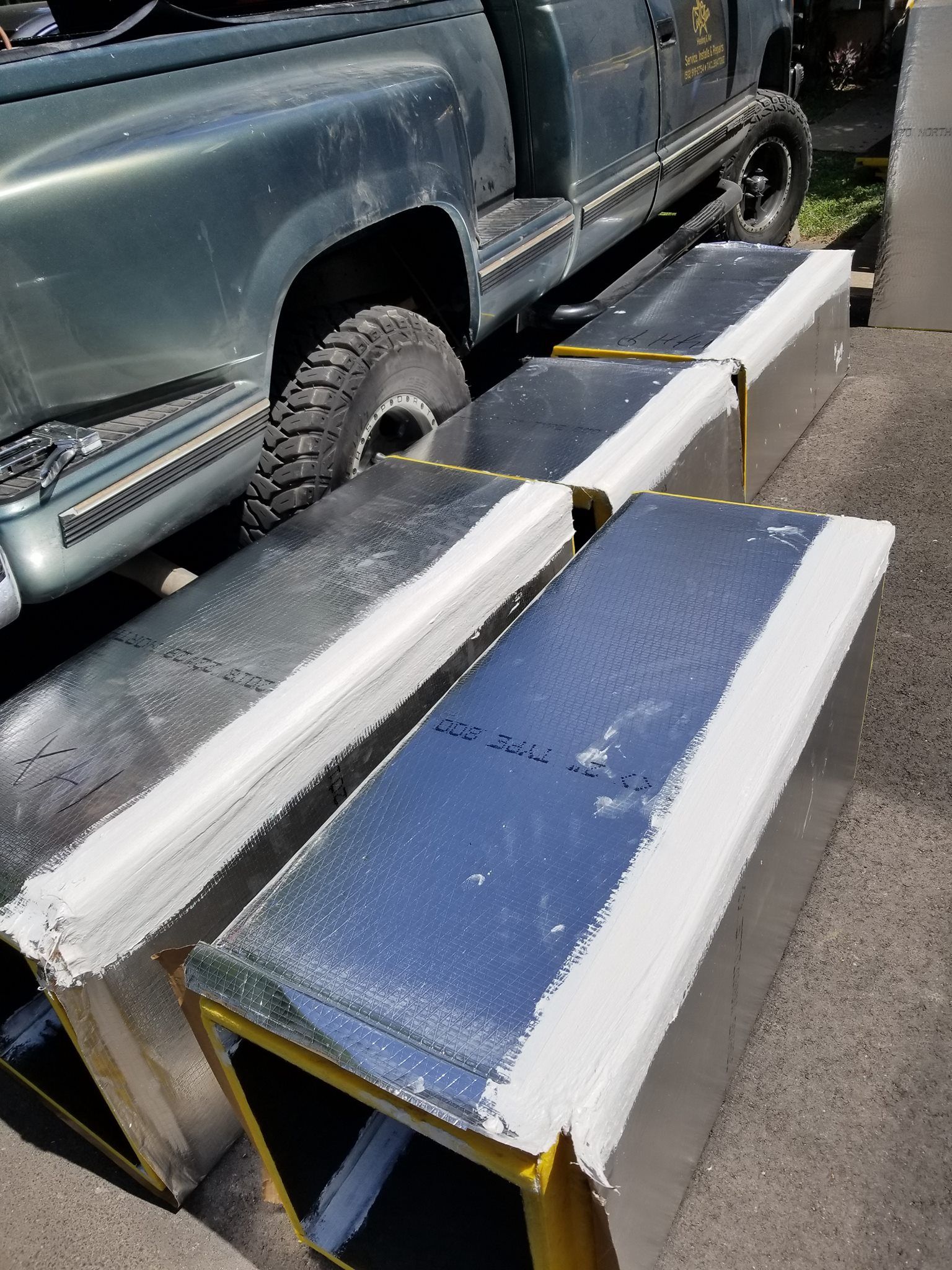 A truck is parked next to a row of ducts on the side of the road.